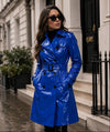 Woman wearing a blue trench coat standing on a city street.
